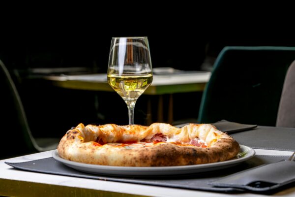 PROSECCO WINES Gourmet pizza with white wine on a restaurant table, perfect for elegant dining experiences.